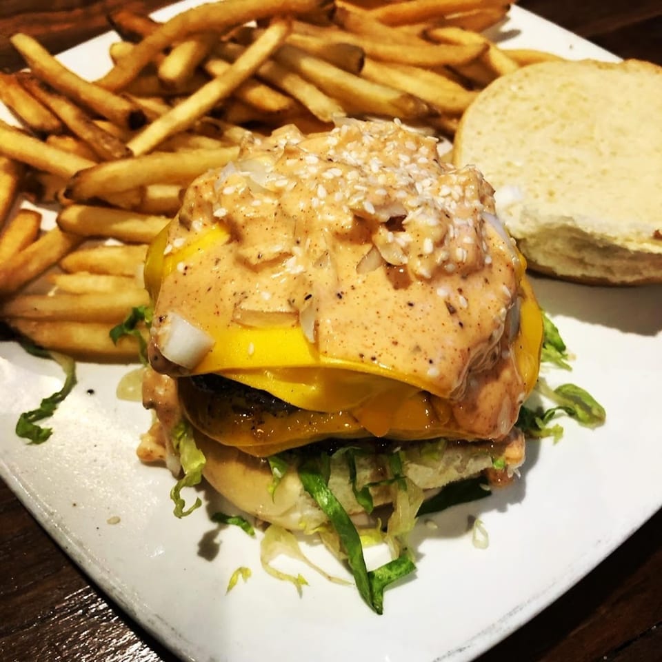 Cheeseburger with special sauce and sesame seeds, served with a side of golden french fries.