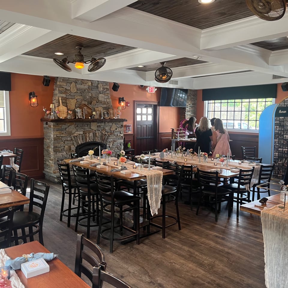 Nanuet Restaurant's dining room with long tables set for an event, featuring a stone fireplace.