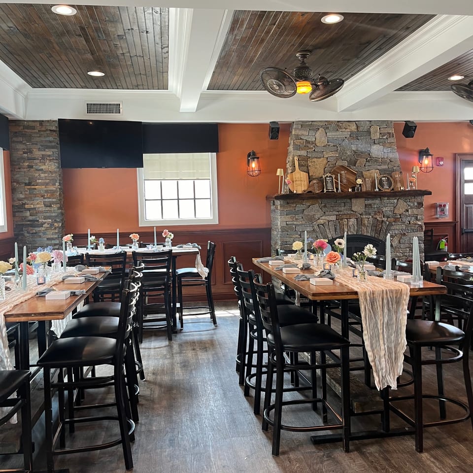 Nanuet Restaurant's dining room with high-top tables set for an event, featuring a stone fireplace.